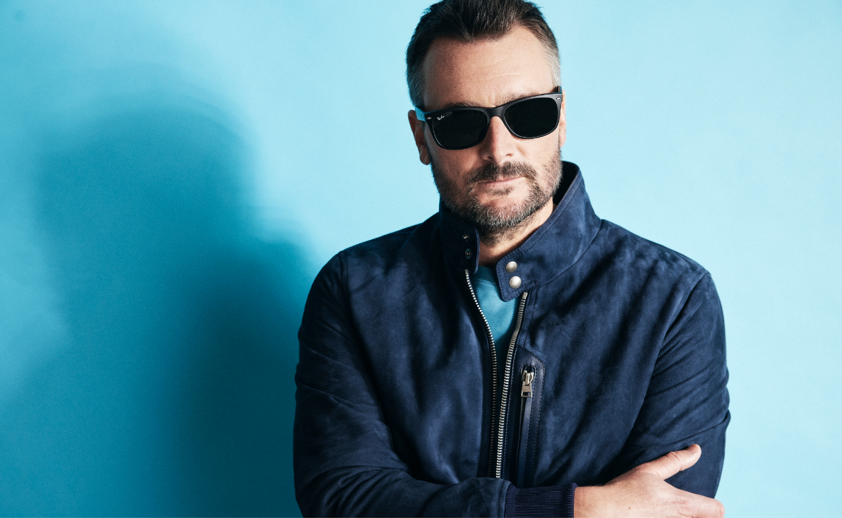 Eric Church in a blue leather coat wearing sun glasses